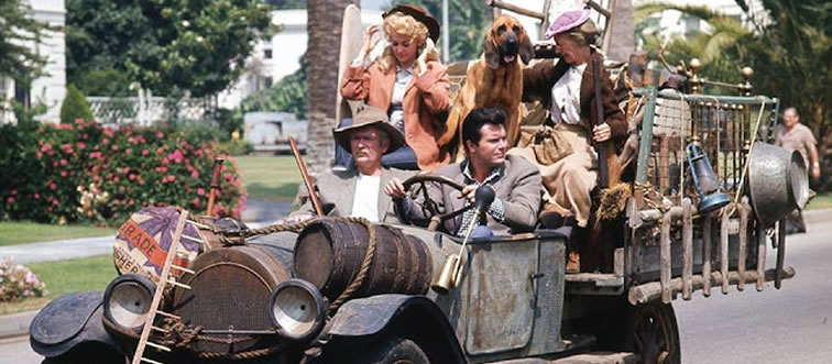 They traded rustic fields for upscale palm trees after striking a golden oil fortune. Name this legendary neighborhood-swap comedy.