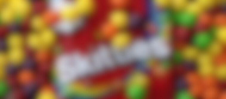 Identify the vibrant, button-shaped treat hiding behind this description: